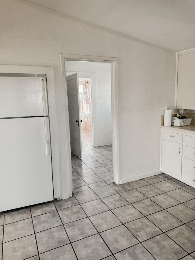 kitchen featuring white refrigerator, white cabinets, and light tile patterned flooring