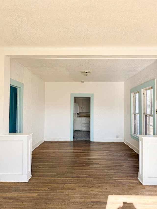 spare room featuring a textured ceiling and dark hardwood / wood-style floors