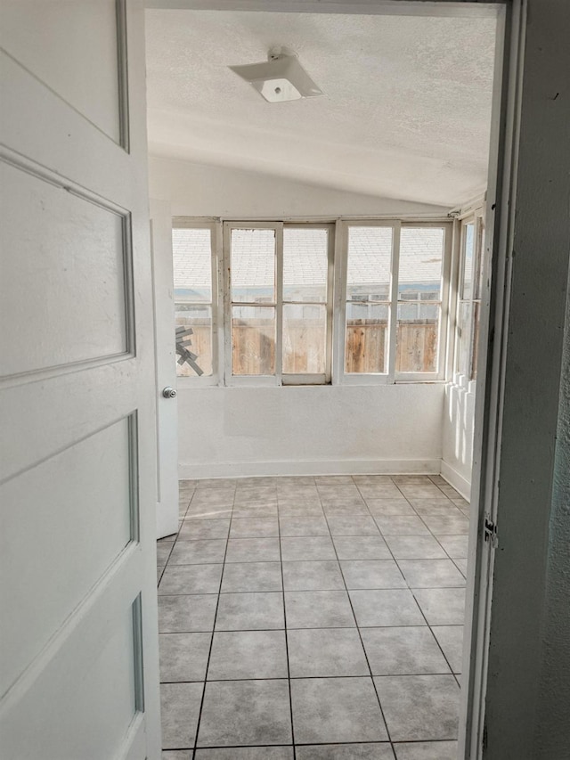 tiled spare room with a textured ceiling and vaulted ceiling