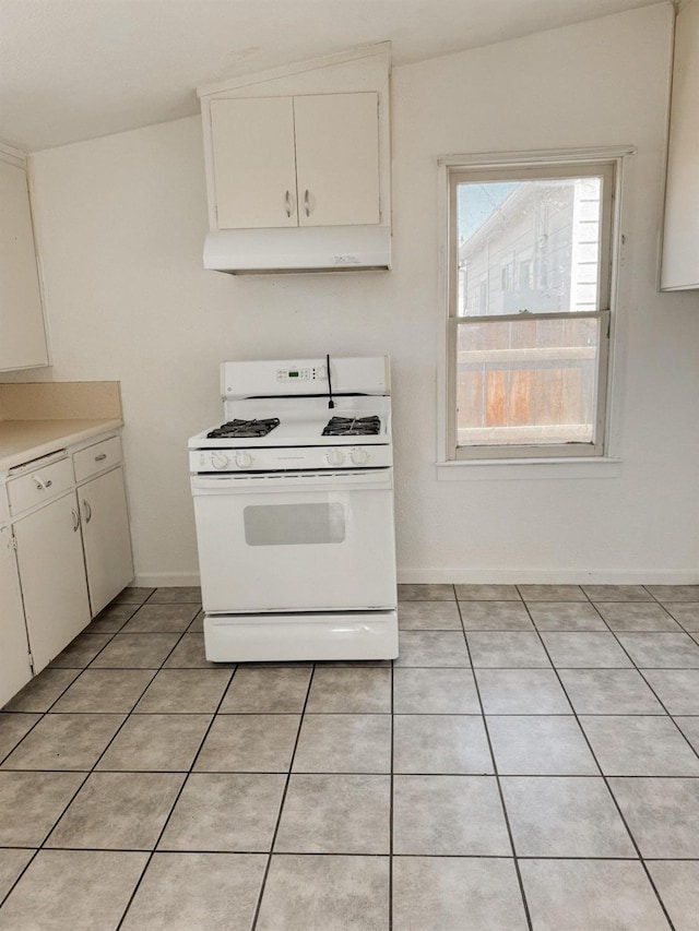 kitchen with white gas stove, white cabinetry, and light tile patterned floors