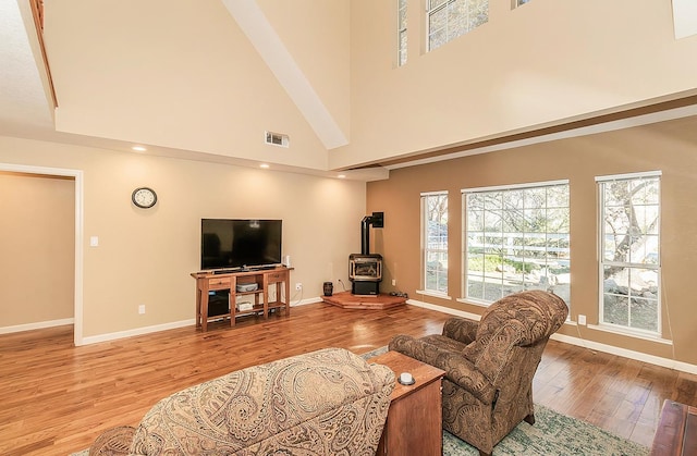 living room featuring a wood stove, a high ceiling, and light wood-type flooring