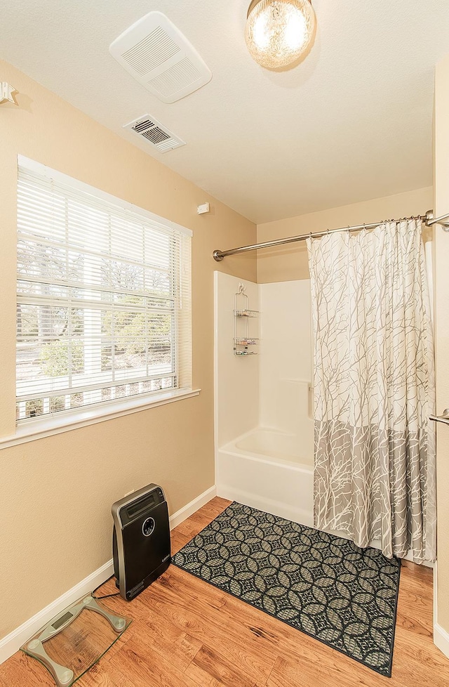 bathroom featuring hardwood / wood-style flooring and shower / bathtub combination with curtain