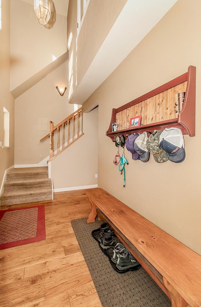 mudroom with light hardwood / wood-style floors and a towering ceiling