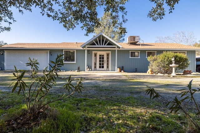 ranch-style home featuring french doors, central AC, and an attached garage