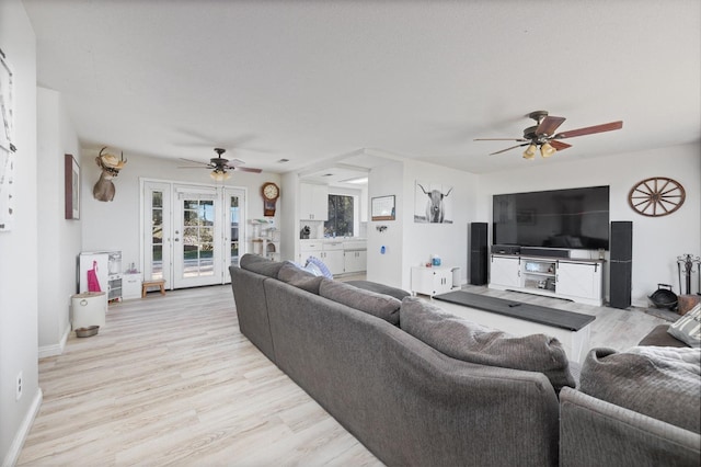 living room with light wood-style floors, ceiling fan, and baseboards