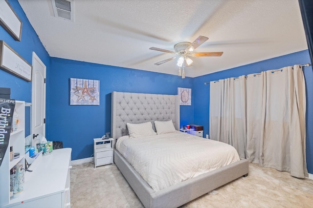 bedroom featuring light colored carpet, visible vents, a ceiling fan, a textured ceiling, and baseboards