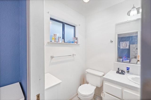 bathroom featuring toilet, tasteful backsplash, and vanity