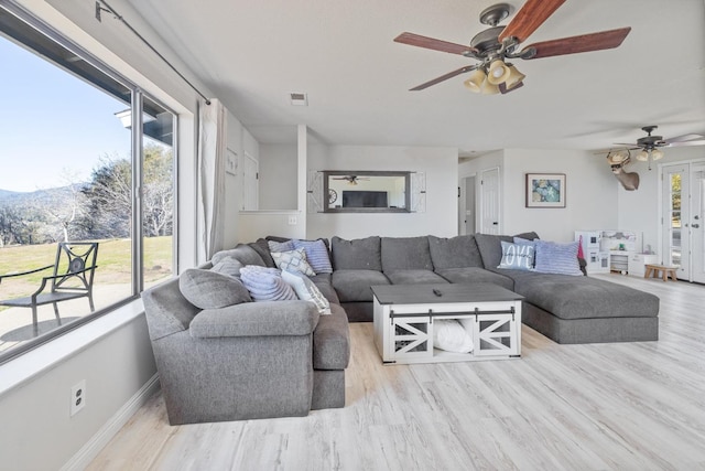 living area featuring a ceiling fan, baseboards, and wood finished floors