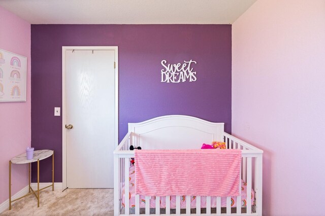 bedroom featuring a nursery area, carpet, and baseboards