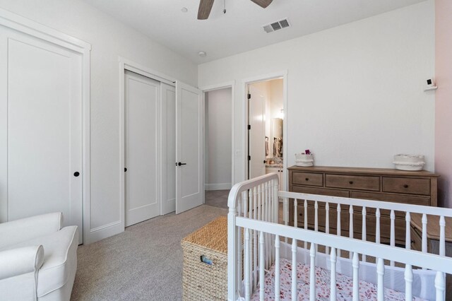 carpeted bedroom featuring ceiling fan, a closet, ensuite bath, and a nursery area