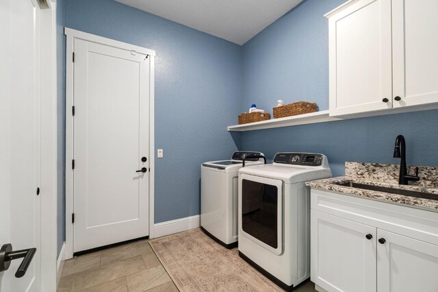 washroom with sink, washer and dryer, and cabinets