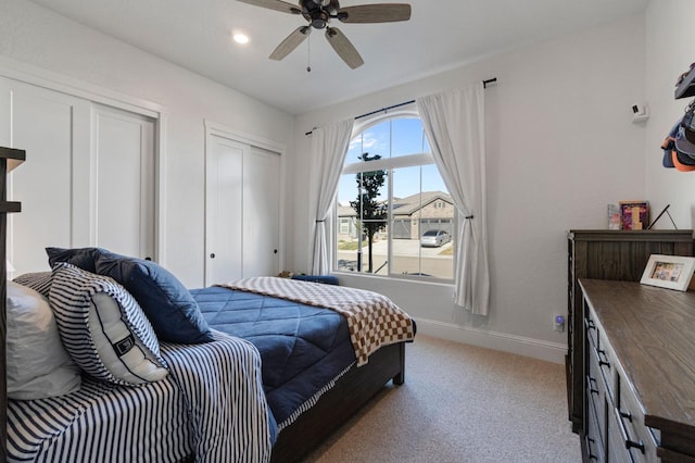 bedroom featuring ceiling fan, two closets, and light carpet