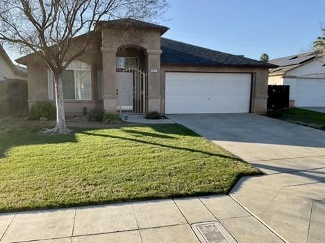 ranch-style home with a garage, concrete driveway, a front lawn, and stucco siding