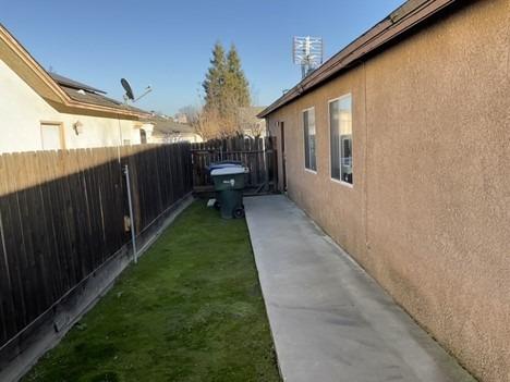 view of property exterior with a yard, fence, and stucco siding