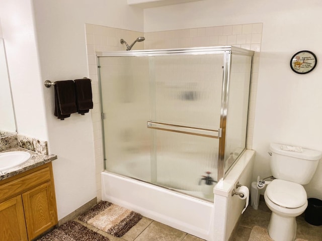 bathroom featuring tile patterned flooring, enclosed tub / shower combo, vanity, and toilet