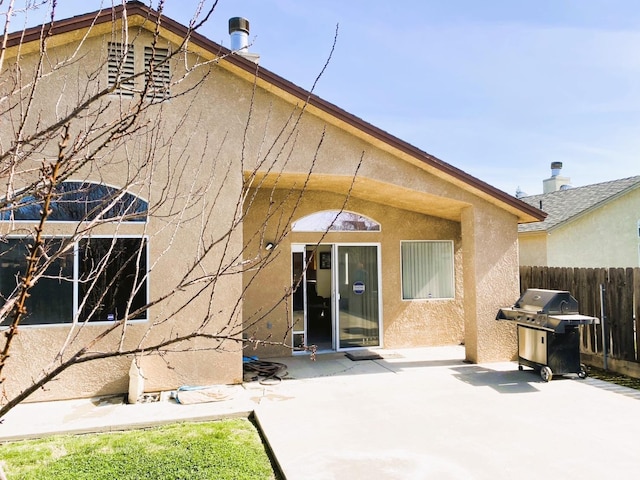 rear view of property with a patio, fence, and stucco siding