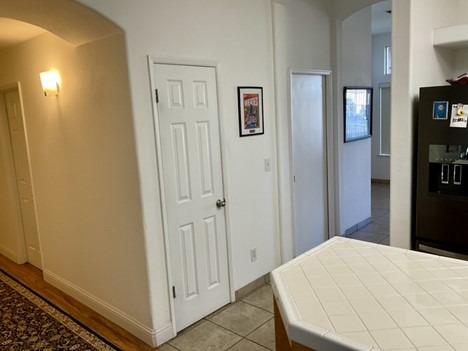 bedroom with arched walkways, black refrigerator with ice dispenser, baseboards, and light tile patterned floors