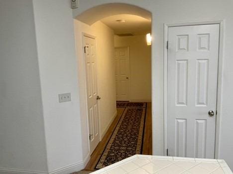 hallway featuring arched walkways and baseboards