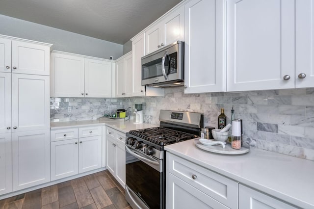 kitchen with white cabinets, decorative backsplash, dark wood-type flooring, and appliances with stainless steel finishes