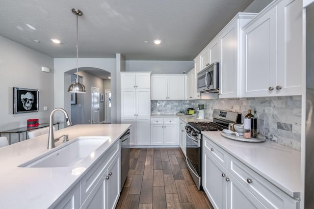 kitchen featuring sink, appliances with stainless steel finishes, white cabinetry, and hanging light fixtures