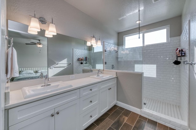 bathroom with a tile shower, vanity, a textured ceiling, and ceiling fan