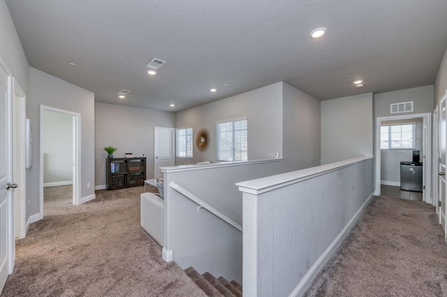 hallway featuring a textured ceiling and light colored carpet