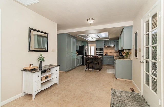 kitchen with stainless steel fridge, black microwave, and decorative backsplash