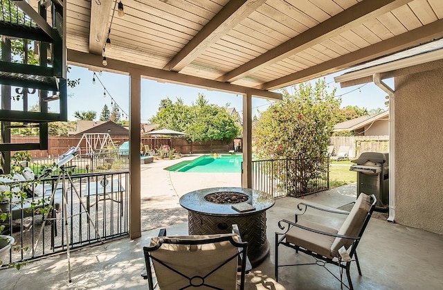 view of patio / terrace featuring a fire pit, a fenced in pool, a storage shed, and grilling area