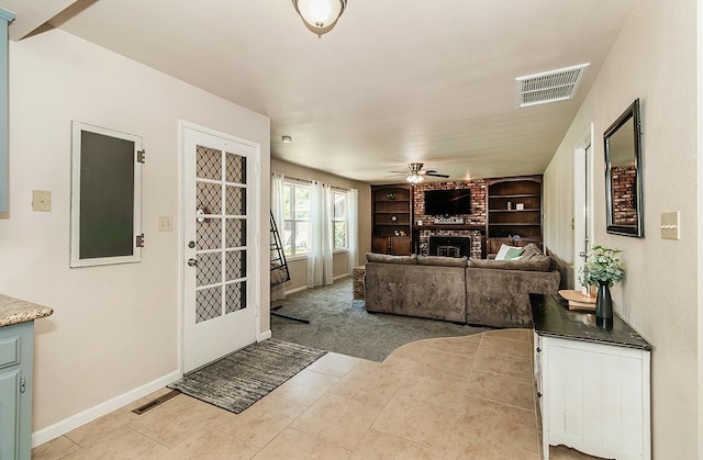 tiled living room with ceiling fan, a brick fireplace, and built in features