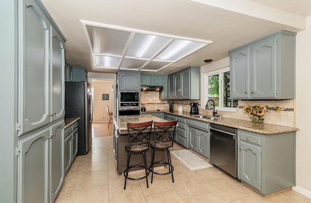 kitchen with sink, a center island, light tile patterned flooring, tasteful backsplash, and black appliances