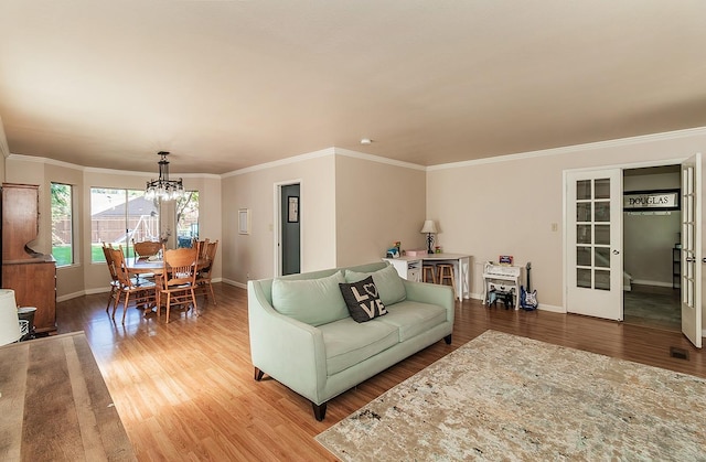 living room featuring an inviting chandelier, french doors, crown molding, and wood-type flooring