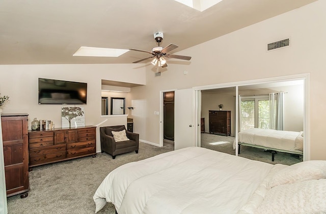 carpeted bedroom with ceiling fan, a walk in closet, lofted ceiling with skylight, and a closet