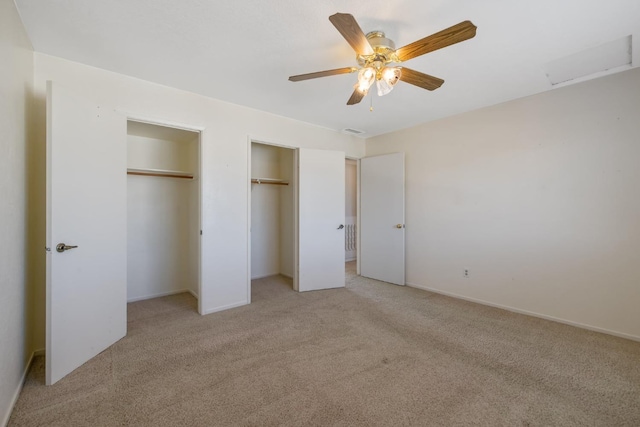 unfurnished bedroom with light colored carpet, ceiling fan, and multiple closets