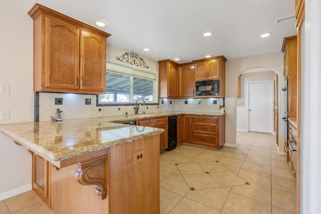 kitchen featuring sink, black microwave, tasteful backsplash, kitchen peninsula, and light stone countertops