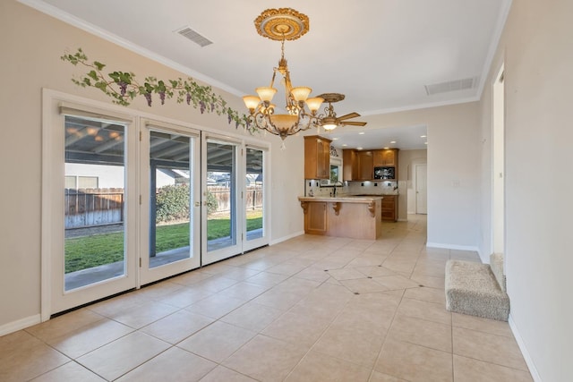 interior space with a notable chandelier, light tile patterned flooring, and crown molding