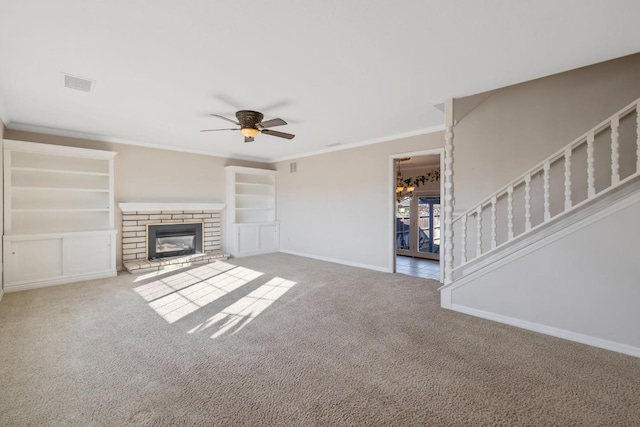 unfurnished living room with ceiling fan with notable chandelier, a brick fireplace, crown molding, and light carpet