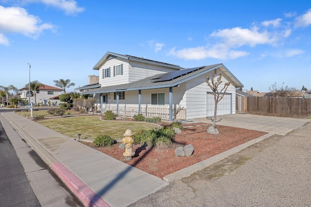 view of front of home featuring solar panels, covered porch, and a garage