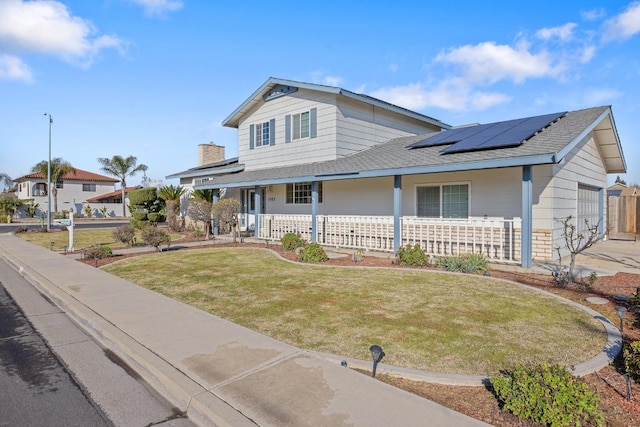 view of front of house with solar panels, a porch, and a front yard