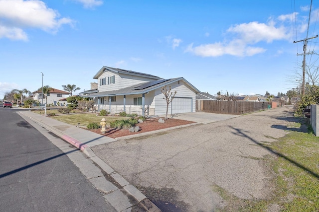 view of front of house featuring a porch, solar panels, and a garage