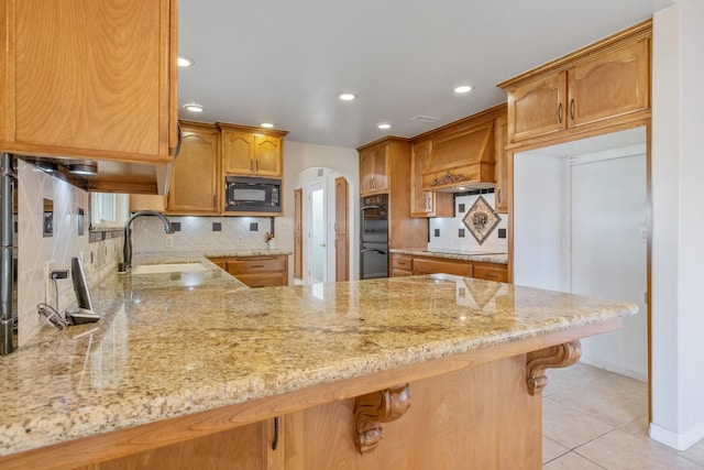 kitchen with sink, kitchen peninsula, backsplash, premium range hood, and black appliances