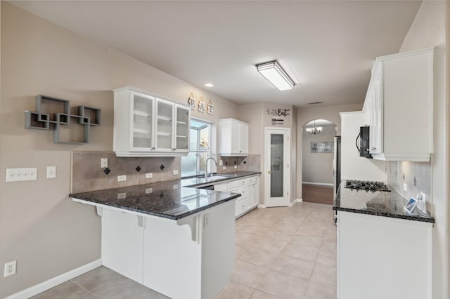 kitchen with kitchen peninsula, white cabinets, appliances with stainless steel finishes, and dark stone countertops