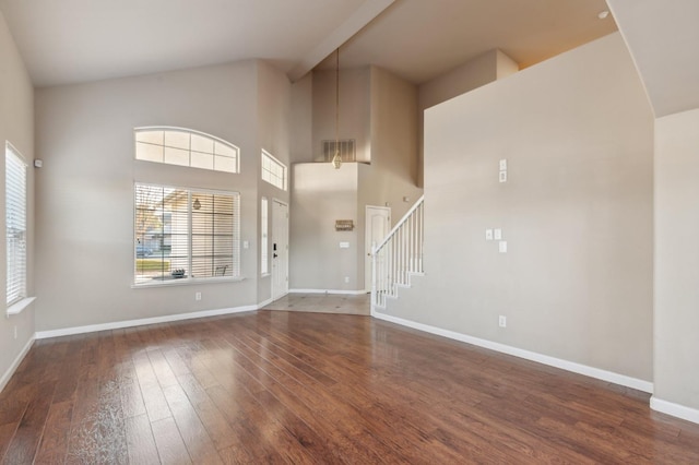 interior space with a towering ceiling and dark hardwood / wood-style floors