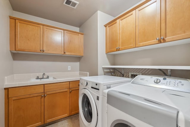 washroom featuring sink, light tile patterned flooring, washing machine and clothes dryer, and cabinets