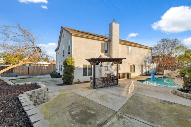 back of house featuring a patio area, a bar, a pergola, and a fenced in pool