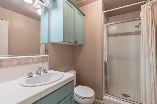 bathroom featuring toilet, a shower with shower door, backsplash, and vanity