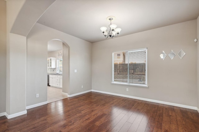 empty room featuring a notable chandelier, wood-type flooring, and plenty of natural light