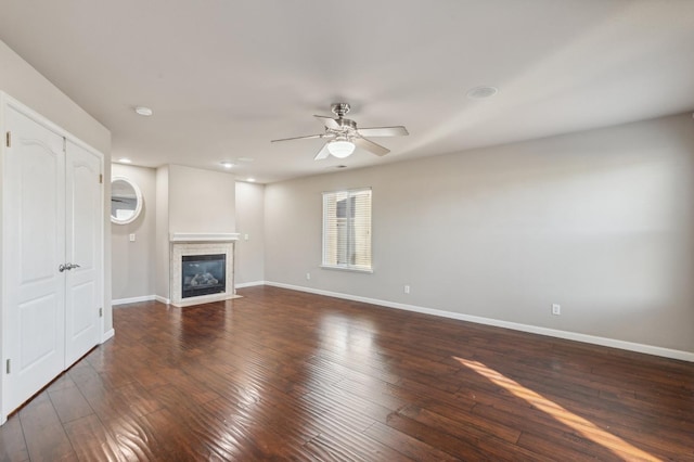 unfurnished living room featuring a fireplace, ceiling fan, and dark wood-type flooring