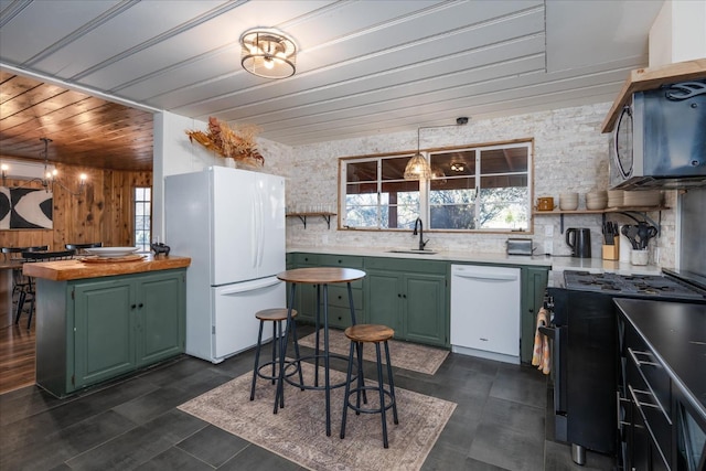 kitchen featuring stainless steel appliances, sink, green cabinets, wood counters, and a notable chandelier