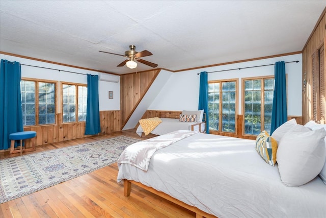 bedroom featuring hardwood / wood-style floors, wooden walls, ceiling fan, and crown molding