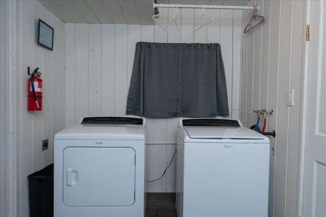 laundry area featuring wood walls and washing machine and dryer